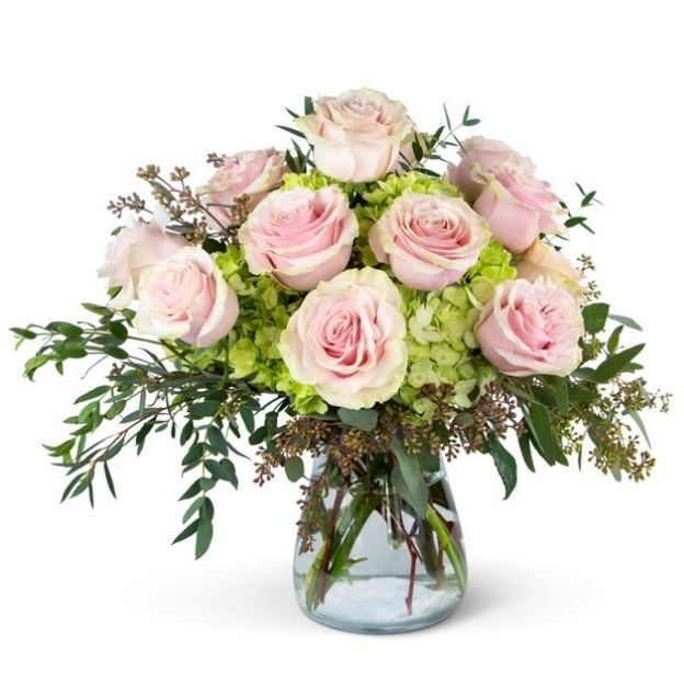 Soft floral arrangement with blush roses, green hydrangeas, eucalyptus, and textured greenery in a vase.